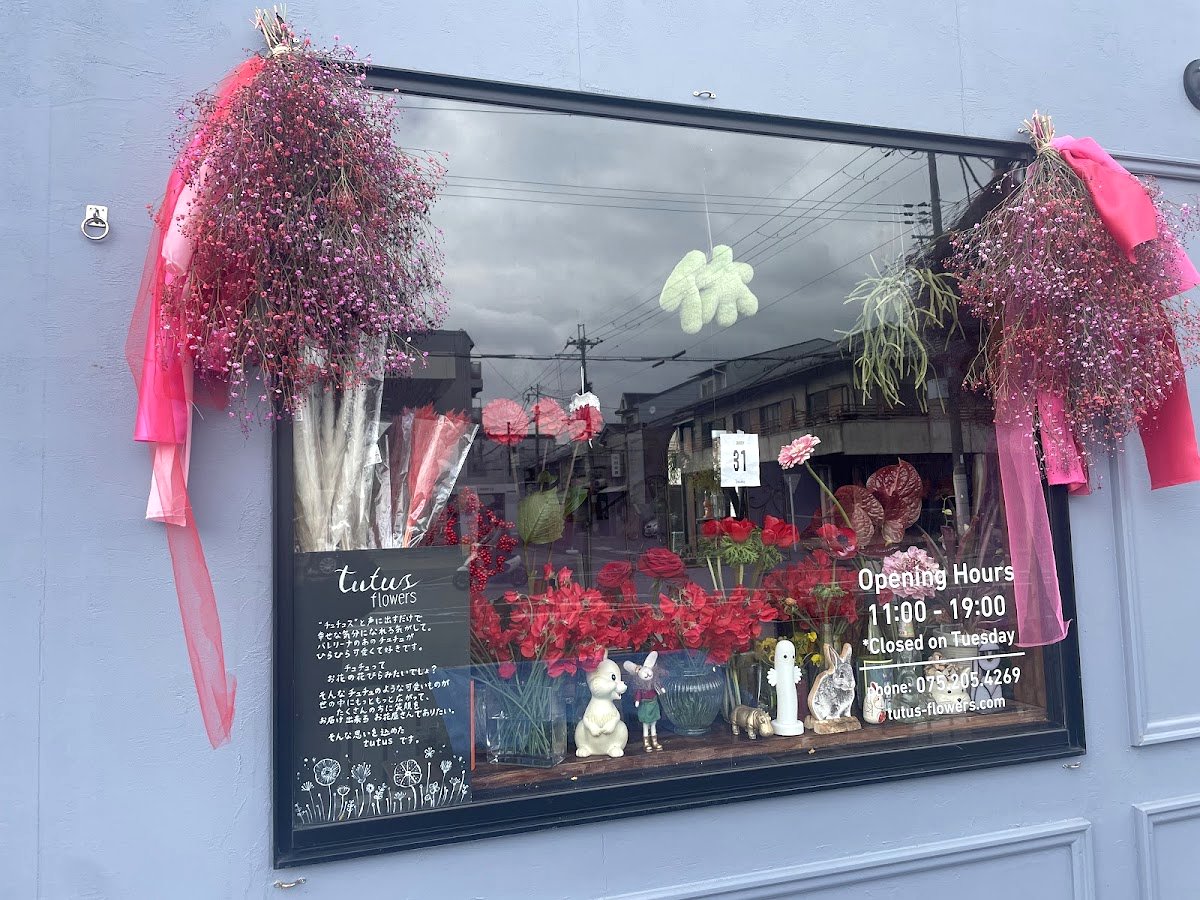 tutus flowersのショーウィンドウ。営業時間の案内と可愛らしい花の装飾